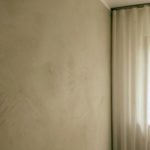 Sonnenschein taucht diese Betonwand in weiches Licht. Unterschiedliche Lichter lassen die Wand in Betonoptik lebendig wirken.