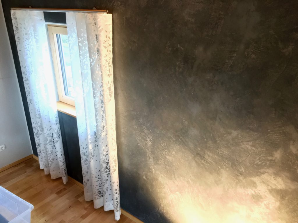 Weißer Wellenvorhang an einer Edelstahlstange vor einer gespachtelten Wand in dunklem Grau – Raumausstattung für Lichtenfels
